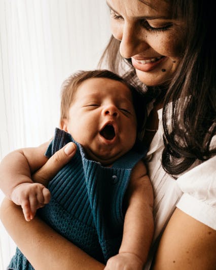 Frau hält ein gähnendes Baby auf dem Arm