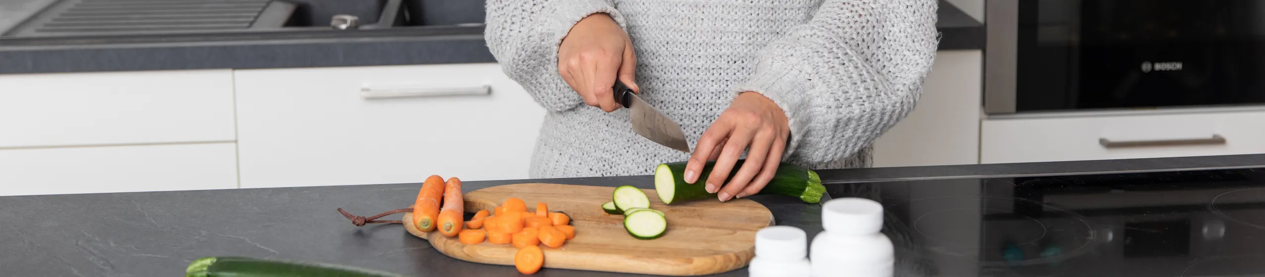 Frau schneidet Gemüse in der Küche