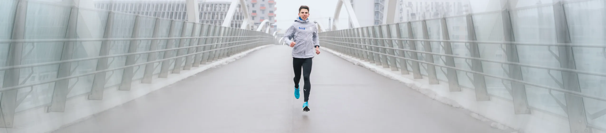 Pure Athlet Aaron Gruen läuft auf einer Brücke