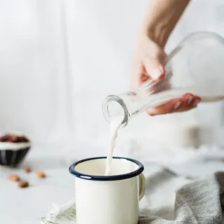 Milch wird in einen Becher geleert