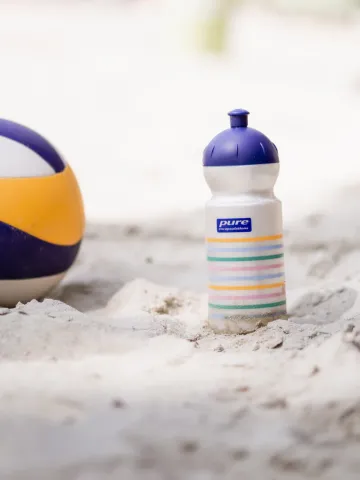Beachvolleyball und Pure Encapsulations Trinkflasche im Sand