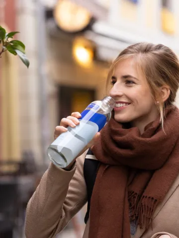 Frau trinkt aus Glas-Wasserflasche