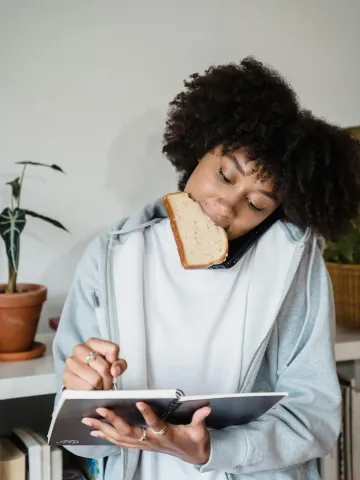 Frau hat ein Brot im Mund notiert konzentriert etwas