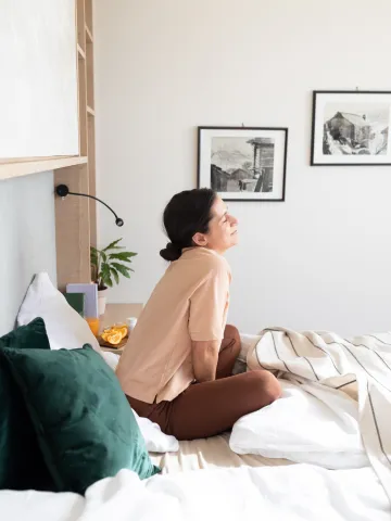 Frau sitzt lächelnd im Bett