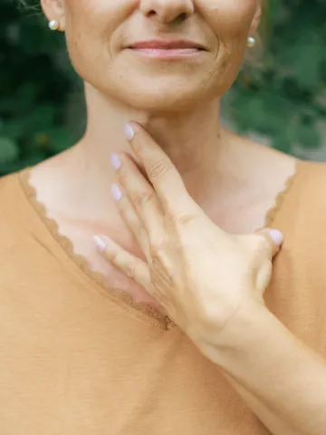 Frau hält Hand an den Hals