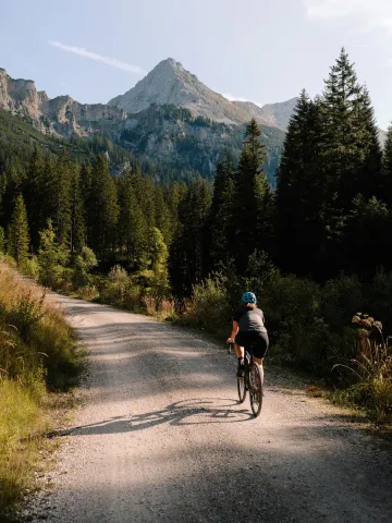Frau fährt mit dem Fahrrad auf einer Bergstraße entlang