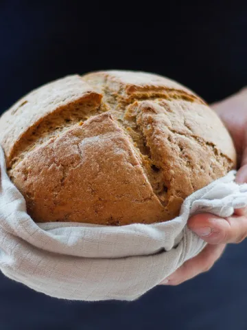 Mann hält frischen Brotlaib in einem Tuch