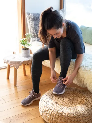 Frau in Sportkleidung bindet sich Schuh zu