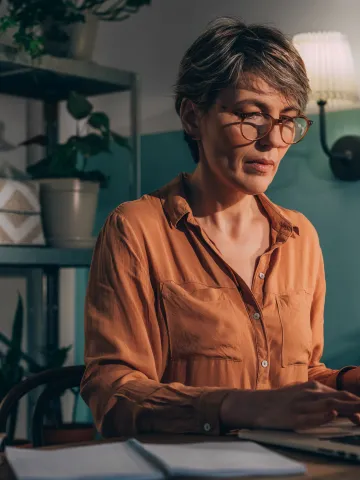 Frau mit Brille arbeitet am Laptop