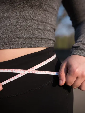 Frau mit Maßband um den Bauch