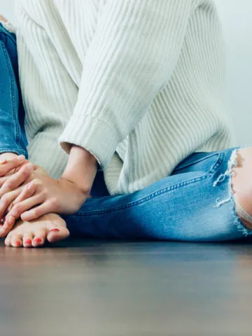 Frau sitzt am Boden und hält nackte Füße