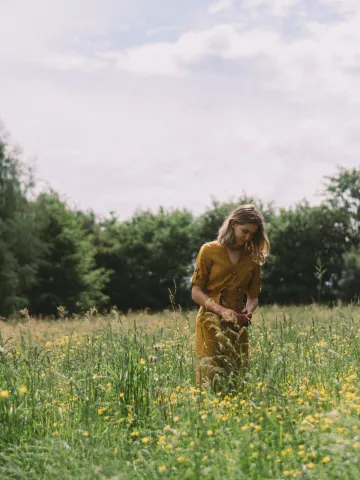 Frau steht in einer Blumenwiese