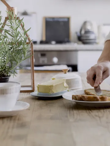 Frau schmiert ein Brot mit Butter