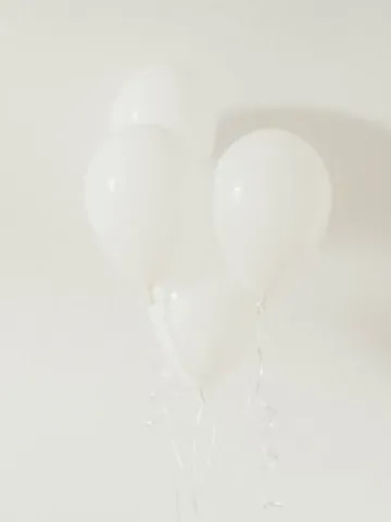 Weiße Luftballons vor weißer Wand