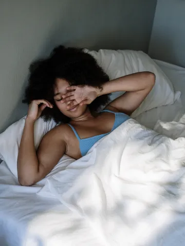 Frau liegt verschlafen im Bett