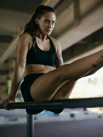 Muskulöse Frau trainiert an einer Stange