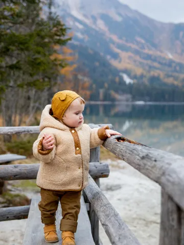 Kind im herbstlichen Outfit in der Natur bei einem See