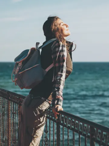 Frau am Meer atmet tief ein