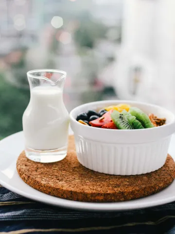 Obst in einer Müslischüssel mit einem Kännchen Milch daneben