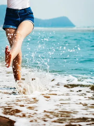Beine am Strand spritzen Wasser