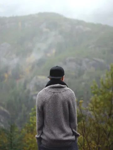 Mann schaut in die Ferne auf eine neblige Berglandschaft