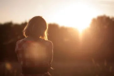 Der Rücken einer Frau in der untergehenden Sonne