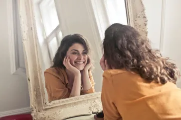Frau steht lächelnd vor dem Spiegel