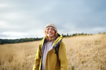 Frau steht in einem herbstlichen Feld
