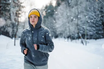 Frau joggt im Winter während es schneit