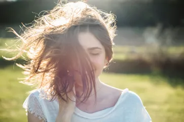 Frau schüttelt ihre Haare in der Sonne