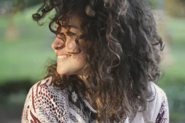 Frau mit dunklen Locken schaut zur Seite