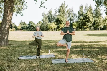 Mann und Frau machen Yoga im Park