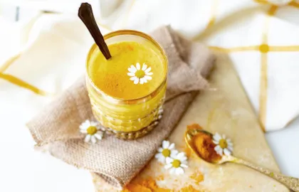 Ein Glas mit Curcuma-Latte und einem Löffel