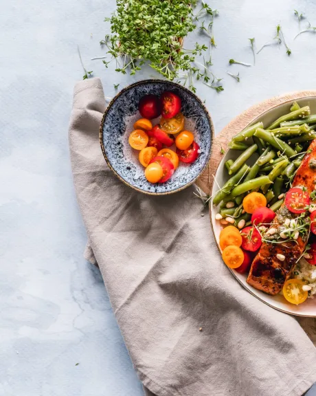 Gefüllter Teller auf Holzbrett mit Spargel, Tomaten Lachs und Quinoa 