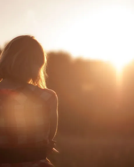 Der Rücken einer Frau in der untergehenden Sonne