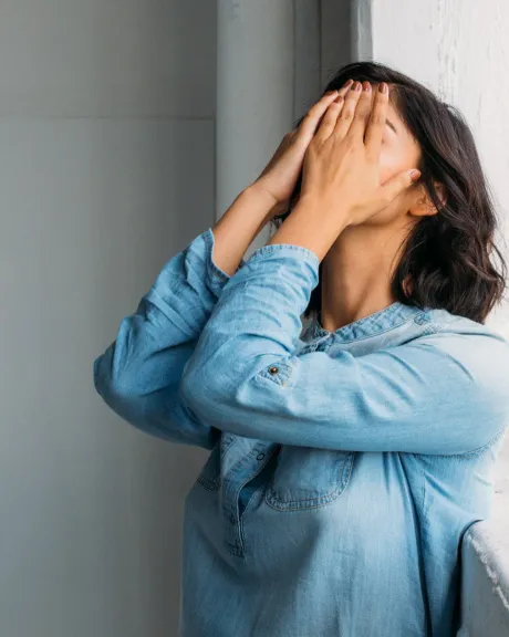 Eine Frau haltet sich die Hände vor das Gesicht