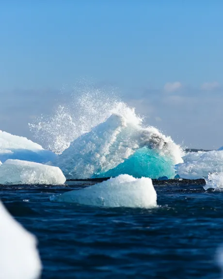 Eisberge im Meer an denen sich eine Welle bricht