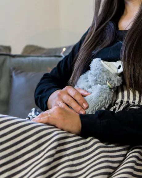 Frau mit Wärmeflasche sitzt auf dem Sofa