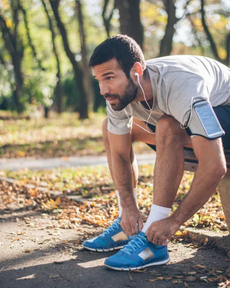 Jogger bindet sich im Park die Schuhe zu