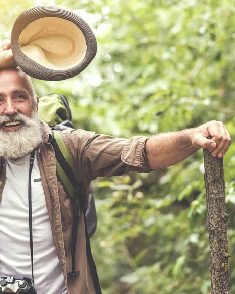 Älterer Mann mit Stock und Hut im Wald