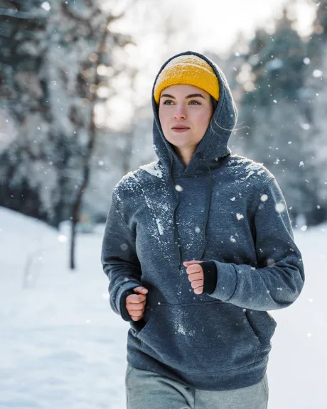 Frau joggt im Winter während es schneit