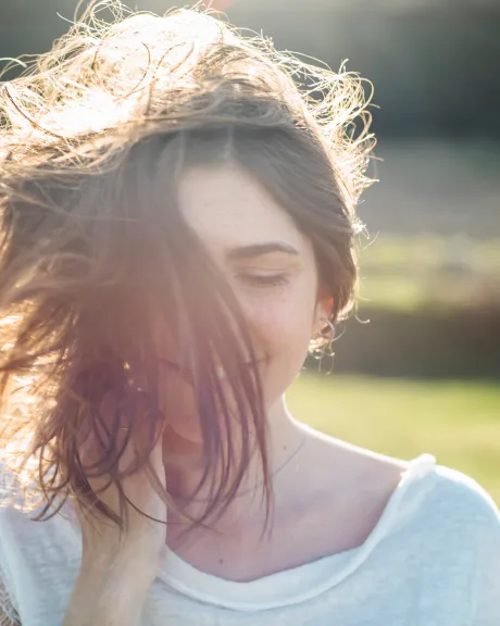 Frau schüttelt ihre Haare in der Sonne