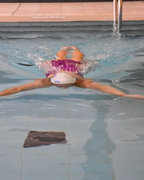 Frau beim Schwimmen mit dem Kopf unterwasser und ausgebreiteten Armen