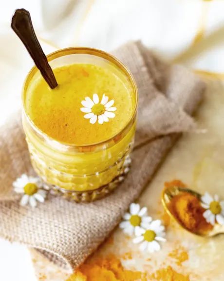 Ein Glas mit Curcuma-Latte und einem Löffel