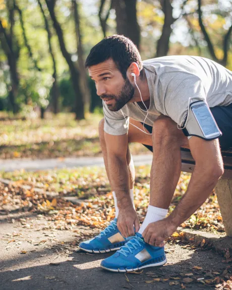 Mann in Sportkleidung schnürt seine Sneaker
