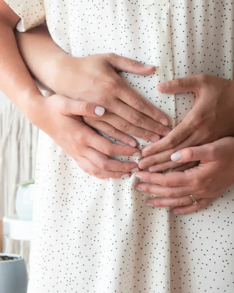 Hände von Frau und Mann halten Schwangerschaftsbauch