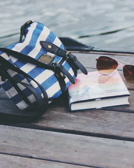 Tasche, Buch und Sonnenbrille auf einem Steg