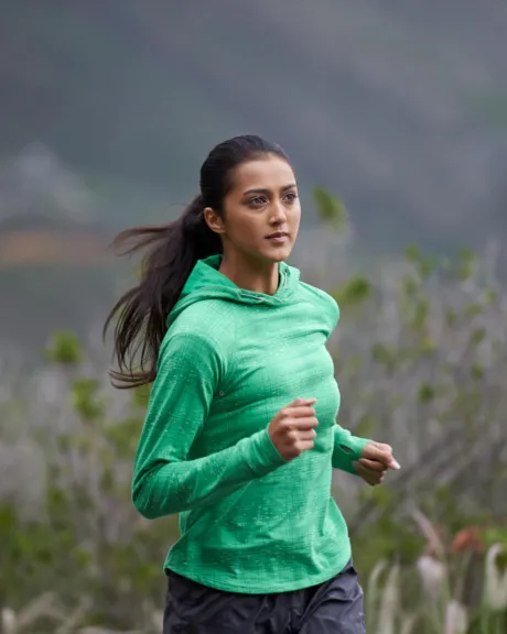 Frau im grünen Pullover läuft in den Bergen