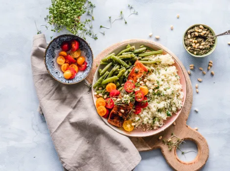 Gefüllter Teller auf Holzbrett mit Spargel, Tomaten Lachs und Quinoa 