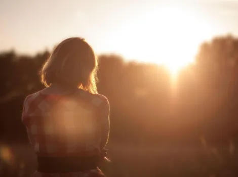 Der Rücken einer Frau in der untergehenden Sonne